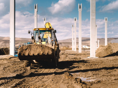 Industrial backhoe excavator and loader carrying earth and working on construction site